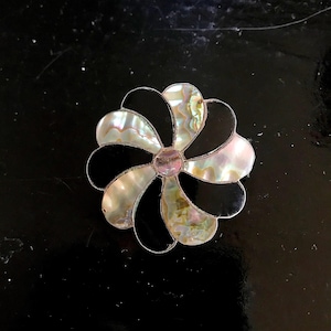 May include: A black and iridescent flower-shaped pin made of mother of pearl and black onyx.