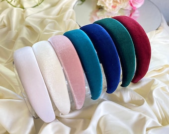 May include: A set of eight velvet headbands in various colors, including white, pink, teal, blue, dark blue, and burgundy. The headbands are arranged in a stack, with the white headband at the bottom and the burgundy headband at the top.
