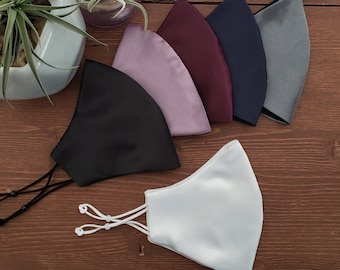 May include: Six different colored satin face masks. The masks are all the same shape and size. The colors are black, white, purple, burgundy, navy blue, and gray.