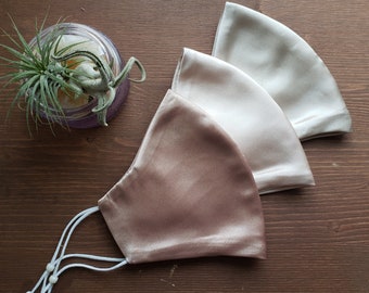 May include: Three silk face masks in different shades of brown. The masks are made of a smooth, silky fabric and have adjustable ear loops.