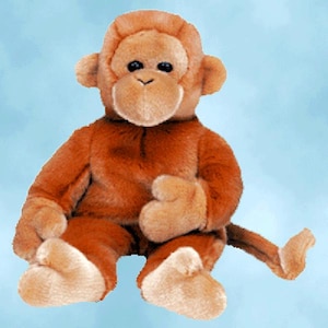 May include: A plush toy monkey with brown fur, a tan face, hands, and feet, and black eyes. The monkey is sitting with its arms and legs outstretched, and its tail is curled behind it. The toy is designed to look like a realistic monkey.