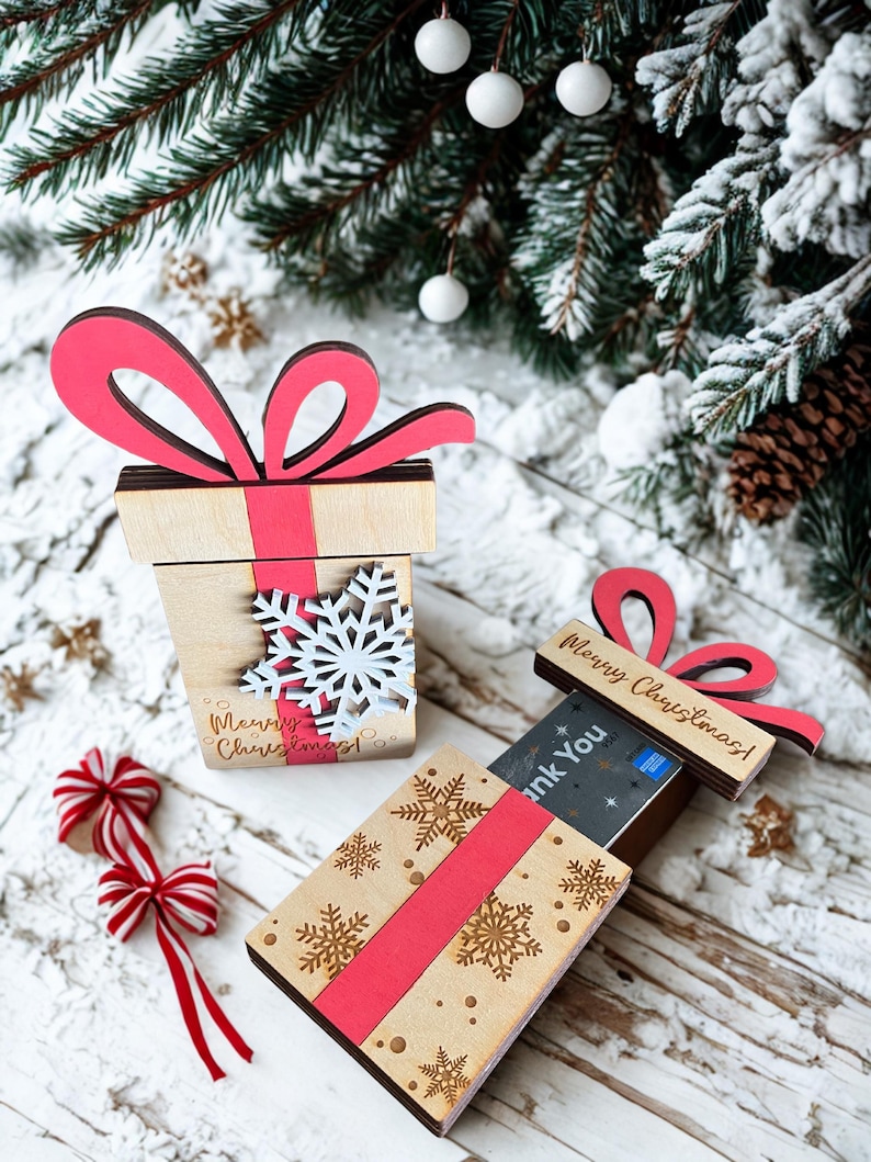May include: Wooden gift box with a red bow and ribbon, decorated with snowflakes. The box has the text "Merry Christmas!" and is designed to hold cards. Festive holiday decor.