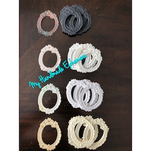 May include: A set of 10 oval-shaped picture frames with ornate designs. The frames are in various colors, including white, cream, black, and a light brown with a green tint. The frames are arranged in three rows on a wooden surface.  The text "My Handmade Ephemera" is visible in the image.