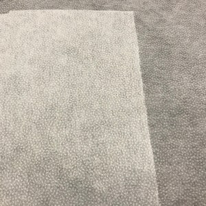 May include: A close-up of two different types of fabric. The top half of the image is a light gray fabric with a textured surface. The bottom half of the image is a white fabric with a similar textured surface.