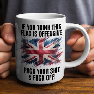 May include: White ceramic mug with a distressed Union Jack flag design. The mug has the text "IF YOU THINK THIS FLAG IS OFFENSIVE PACK YOUR SHIT & FUCK OFF!" printed in black. The mug is held by a person, with the handle visible.