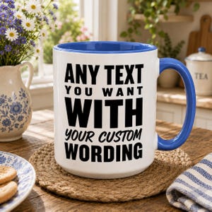 May include: A white ceramic mug with a bright blue interior and handle. The front of the mug features bold black text that reads: ANY TEXT YOU WANT WITH YOUR CUSTOM WORDING. The mug has a cylindrical body and a curved handle on the right side.