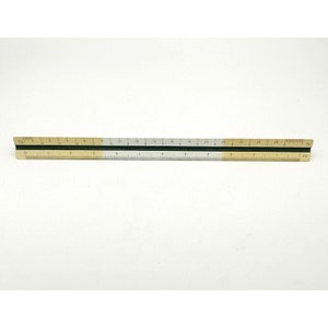 May include: A 36-inch ruler with a black edge and a white and gold scale. The ruler is divided into inches and fractions of an inch.