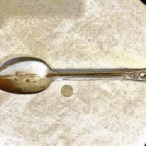 Large rustic vintage metal spoon with decorative handle.