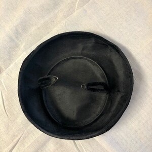 May include: A black velvet hat with a wide brim and a simple design.