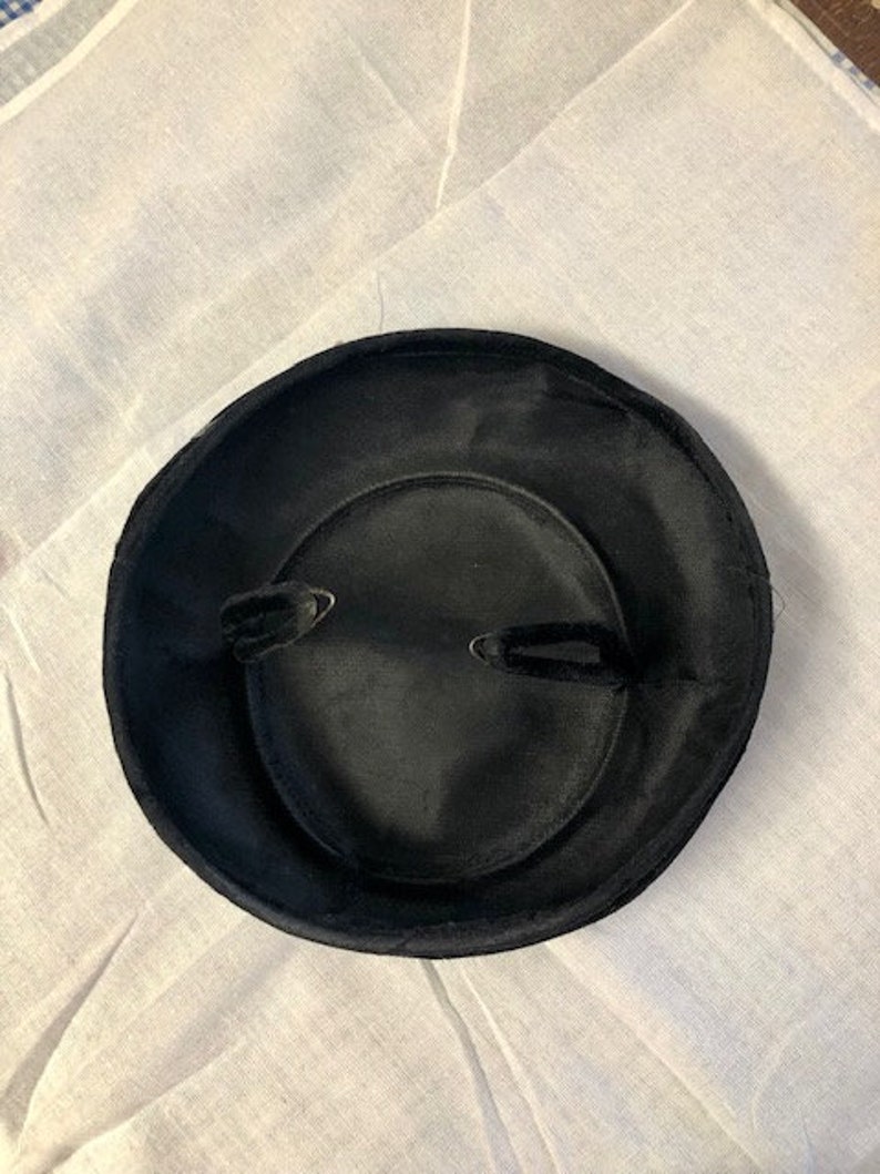 May include: A black velvet hat with a wide brim and a simple design.