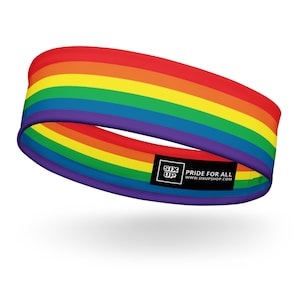 May include: A circular headband featuring horizontal stripes in red, orange, yellow, green, blue, and purple. A black rectangular label is attached to the lower edge, displaying the white text SIX UP PRIDE FOR ALL WWW.SIXUPSHOP.COM.