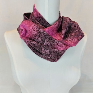 Könnte beinhalten: Ein pinkfarbener und schwarzer Infinity-Schal mit floralem Muster.