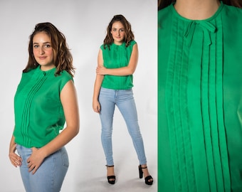 May include: A green sleeveless blouse with a bow at the neckline and pleats down the front. The blouse is made of a sheer fabric.