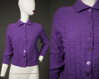 May include: A purple knitted cardigan with a button-up front and a collared neckline.