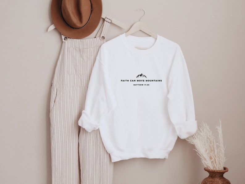 May include: White long-sleeve sweatshirt with the text "Faith can move mountains" and "Matthew 17:20" printed on the front.