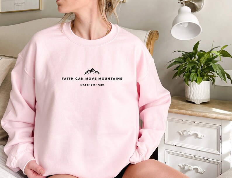 May include: Pink sweatshirt with the text "Faith can move mountains" and "Matthew 17:20" in black.