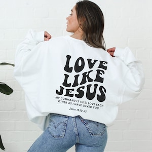 May include: White sweatshirt with the text "LOVE LIKE JESUS" in black retro font. The text "MY COMMAND IS THIS: LOVE EACH OTHER AS I HAVE LOVED YOU. John 15:12-13" is printed below in smaller black font.