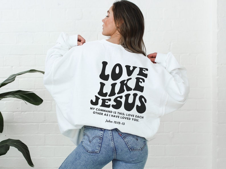 May include: White sweatshirt with the text "LOVE LIKE JESUS" in black retro font. The text "MY COMMAND IS THIS: LOVE EACH OTHER AS I HAVE LOVED YOU. John 15:12-13" is printed below in smaller black font.