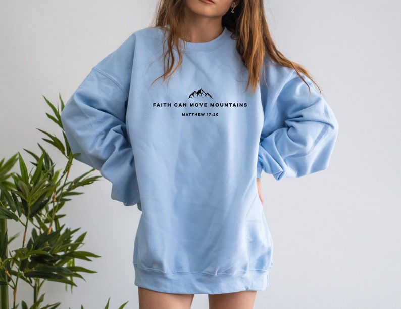 May include: A light blue sweatshirt with the text "Faith can move mountains" and "Matthew 17:20" printed on the front.