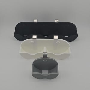 May include: Three wall-mounted organizers for storing items. The top organizer is black and has three compartments. The middle organizer is white and has two compartments. The bottom organizer is gray and has one compartment.