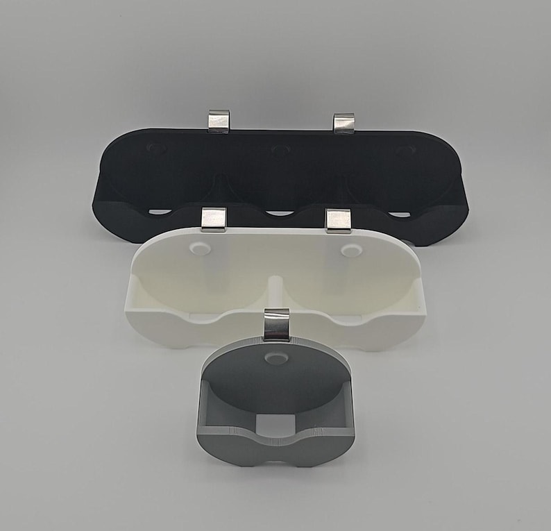 May include: Three wall-mounted organizers for storing items. The top organizer is black and has three compartments. The middle organizer is white and has two compartments. The bottom organizer is gray and has one compartment.