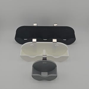 Puede incluir: Tres estantes de pared para organizar art&iacute;culos peque&ntilde;os. Los estantes est&aacute;n hechos de pl&aacute;stico negro, blanco y gris y tienen clips met&aacute;licos para colgar.