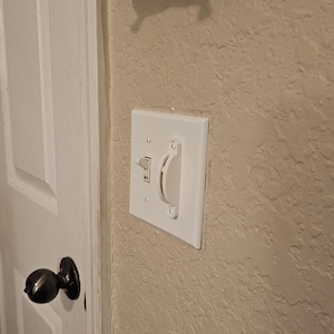 May include: A white light switch with a rocker switch and a dimmer switch. The switch is mounted on a white wall.
