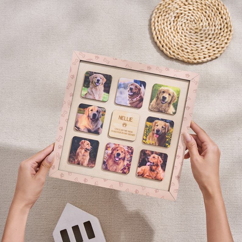 Puede incluir: Un collage de fotos de perros personalizado en un marco rosa claro. El marco contiene nueve fotos cuadradas de un golden retriever, con una placa de madera que dice "NELLIE, ONCE BY MY SIDE, FOREVER IN MY HEART".