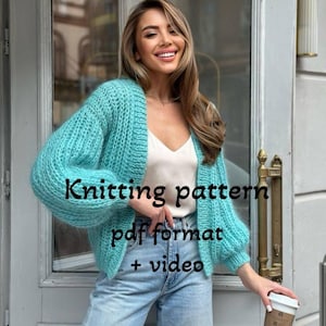 Puede incluir: Cárdigan de punto turquesa con diseño amplio y abierto y mangas largas. El texto "Knitting pattern pdf format + video" se muestra en la imagen. El cárdigan se combina con vaqueros azul claro.
