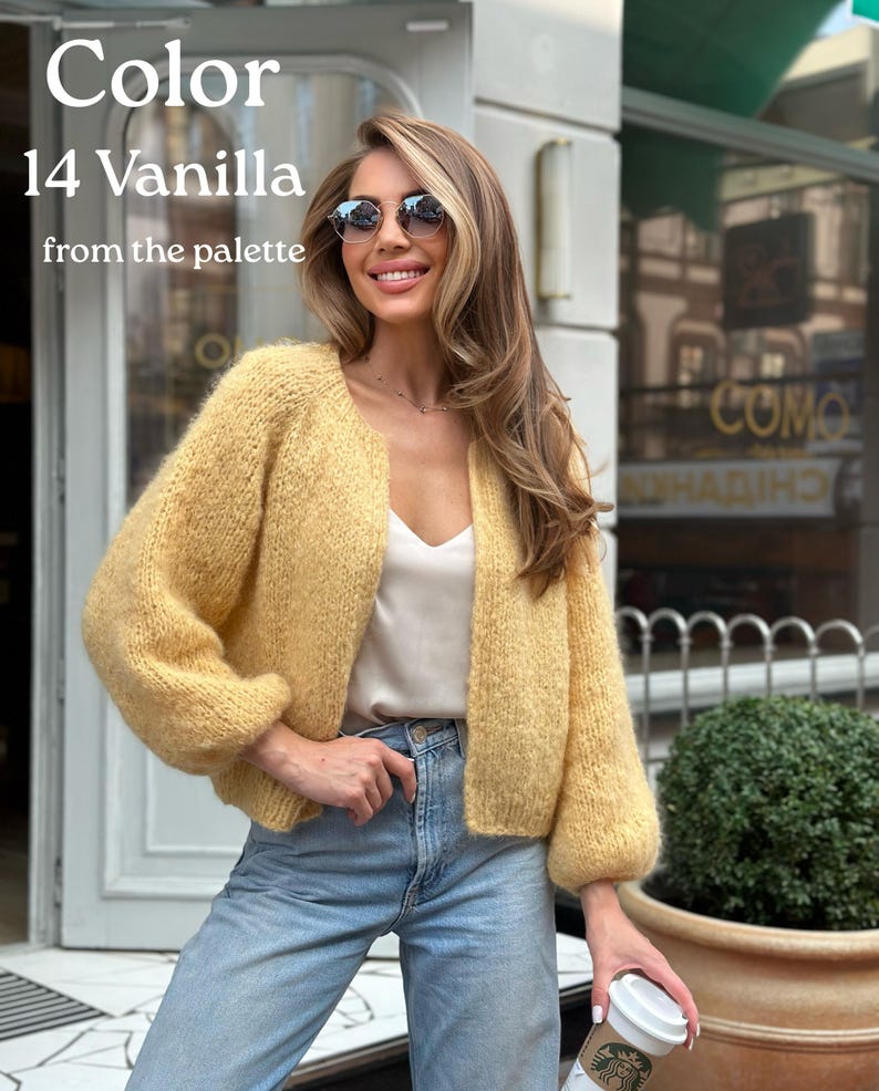 May include: A soft, chunky knit cardigan in a pale yellow vanilla colour with long sleeves and an open front. The garment is worn over a simple cream-coloured camisole and light blue denim jeans. Text on the image reads Color 14 Vanilla from the palette.
