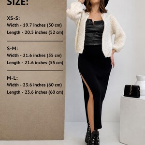 May include: A cream-coloured knit cardigan with long sleeves, worn with a black leather-look top and a black midi skirt featuring a side slit. The image includes a size chart listing widths and lengths from 50 cm to 60 cm for sizes XS-L.