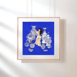May include: A woman sits amongst a collection of blue and white porcelain vases and bowls against a bright blue background. The vases are decorated with intricate floral patterns and the woman is wearing a white dress.