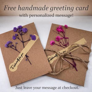 May include: Two handmade greeting cards with dried flowers and the text "Especially for you." One card features purple flowers, the other pink. The cards are tied with twine and a beige label. The text "Free handmade greeting card with personalized message!" is at the top.