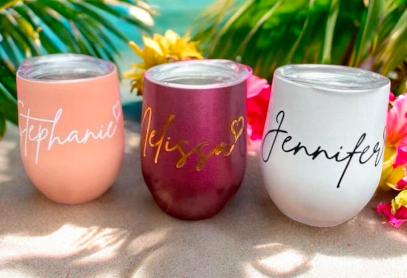 May include: Three personalised stainless steel wine tumblers with the names Stephanie, Melissa, and Jennifer. The tumblers are in pink, burgundy, and white.