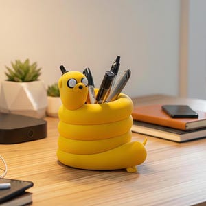 May include: A yellow, cylindrical desk organizer shaped like a coiled cartoon dog character with large white eyes and a black nose. The hollow center holds several black and silver pens and markers, with the dog's head extending from the top rim.