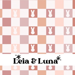 May include: A repeating pattern of squares in shades of pink, peach, and white, featuring white bunny silhouettes. The design includes the text "Leia & Luna" in a whimsical font, suitable for children's products or Easter-themed items.
