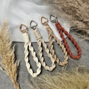 Op de afbeelding: Vier sleutelhangers met hartvormige sluitingen en gedraaide touwontwerpen in tinten bruin, beige en wit.
