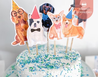 May include: A white frosted cake topped with five dog-themed paper cutouts on sticks. The dogs include a spaniel with glasses, a French bulldog with a bowtie, a dachshund with pink glasses, a chihuahua with a pink bow, and a corgi in a hat.