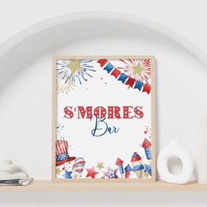 May include: A framed sign with a white background, featuring the text "S'MORES Bar" in red and blue. The design includes watercolor illustrations of fireworks, a patriotic hat, ice cream, and stars, with a wooden frame.