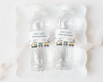 May include: Two clear plastic water bottles featuring custom labels with a watercolor train illustration and the text Oscar's Third Birthday. The labels display a colorful locomotive and train cars against a soft, light-colored background.