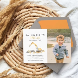 May include: A rectangular birthday invitation card featuring a watercolor excavator illustration, the text CAN YOU DIG IT?! DYLAN IS TURNING TWO, and event details. A photograph of a young child is on the right side, paired with a gray envelope.