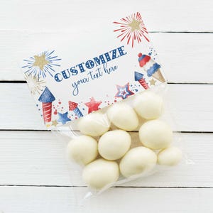May include: A clear plastic bag filled with white round candies, topped with a rectangular paper header featuring red, white, and blue fireworks, stars, and ice cream illustrations with the text CUSTOMIZE your text here.