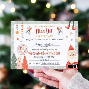 Puede incluir: Un certificado navideño con el texto "Nice List Certificate" y el nombre "Beau Johnson". El certificado presenta un diseño con Papá Noel, copos de nieve, estrellas y árboles de Navidad. La fecha en el certificado es el 24 de diciembre de 2021.