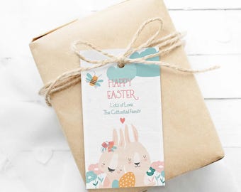 Puede incluir: Una etiqueta de regalo rectangular blanca atada con cordel a un paquete envuelto en papel marrón. La etiqueta muestra una abeja, nubes azules y dos conejos entre flores. El texto dice: HAPPY EASTER, Lots of Love, The Cottontail Family, con un corazón rojo.