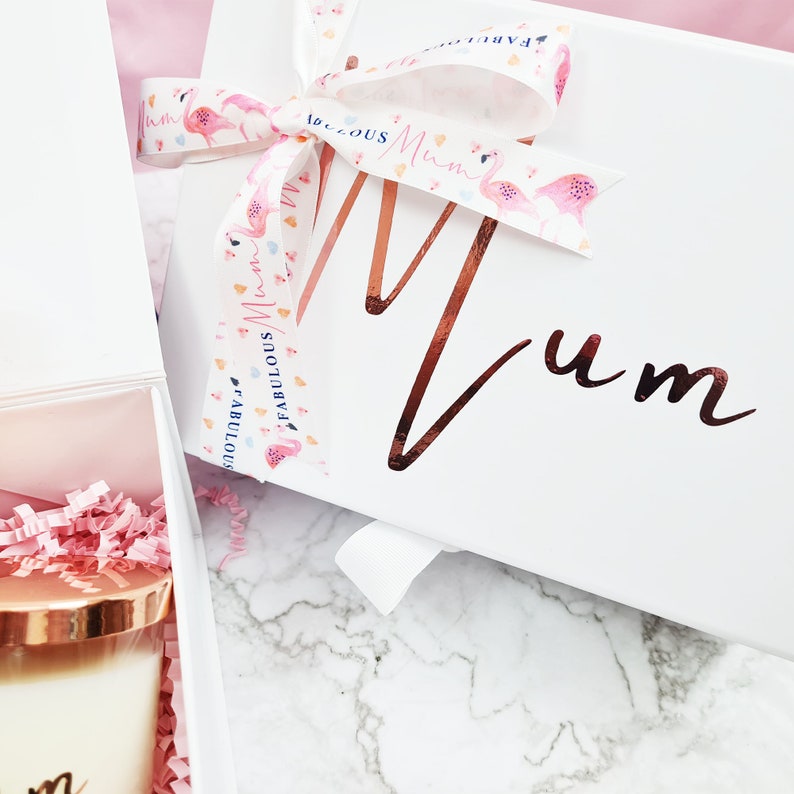 K&ouml;nnte beinhalten: Wei&szlig;e Geschenkbox mit einem rosa-wei&szlig;en Band, auf dem der Text "Fabulous Mum" steht. Die Box hat eine ros&eacute;goldene Aufschrift "Mum".