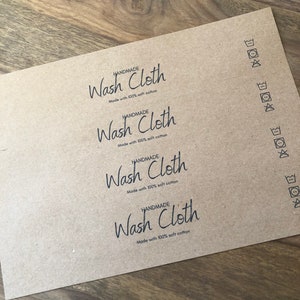 以下が含まれることがあります： 4枚の茶色の紙ラベルに「HANDMADE Wash Cloth Made with 100% soft cotton」というテキストが印刷されています。ラベルには、右側に洗濯表示のシンボルも印刷されています。