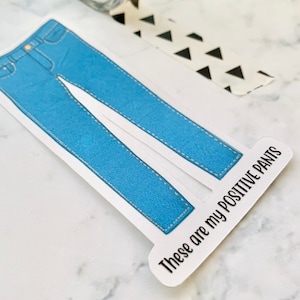 May include: A blue denim sticker with the text "These are my positive pants" on a white background.