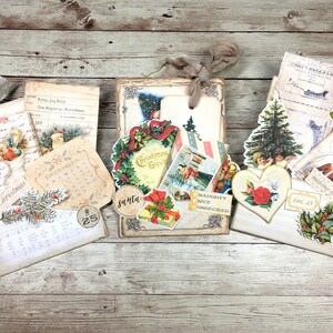 May include: A collection of vintage Christmas decorations and ephemera, including a wreath, a calendar, a Christmas tree, and a heart-shaped ornament. The decorations are arranged on a wooden surface and feature a variety of colors, including red, green, and gold.