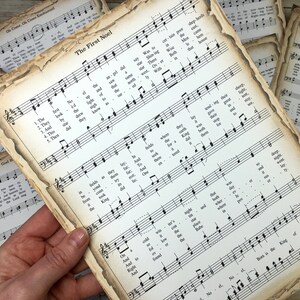 Pu&ograve; includere: Un primo piano di una pagina di musica vintage con le parole "The First Noel" stampate in alto. La musica &egrave; per un canto natalizio e include il testo e le note musicali. La carta &egrave; invecchiata e ha un aspetto ingiallito e usurato.
