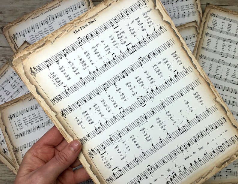 Pu&ograve; includere: Un primo piano di una pagina di musica vintage con le parole "The First Noel" stampate in alto. La musica &egrave; per un canto natalizio e include il testo e le note musicali. La carta &egrave; invecchiata e ha un aspetto ingiallito e usurato.